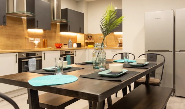Dining table with place settings and modern kitchen. at Electric Press in Sheffield Student Accommodation