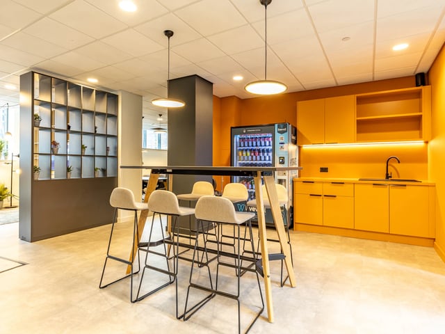 Bar stools at high table with vending machine and kitchen. at Straits Manor in Sheffield Student Accommodation