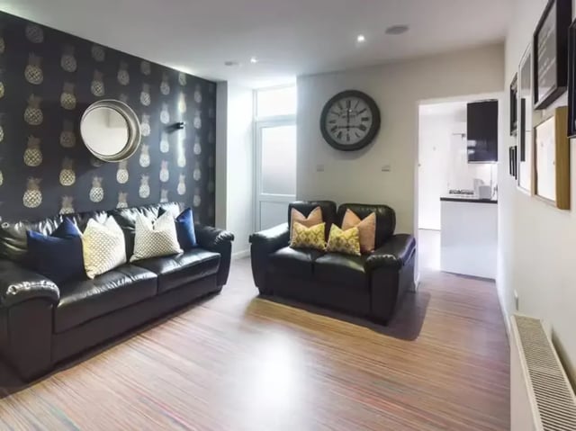 Leather sofas patterned wallpaper clock large room living room at 15 Carlton Road in Stoke-On-Trent Student Accommodation