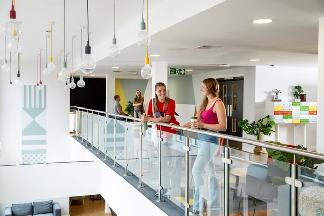 Students chatting on landing with modern decor common area at Beech House in Oxford Student Accommodation