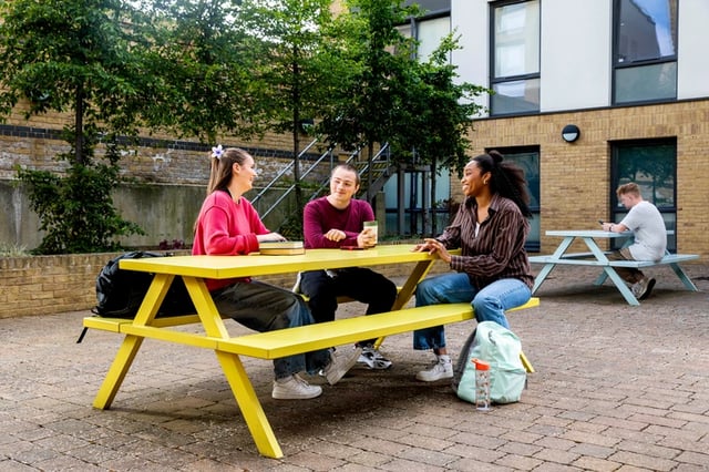 Three students at yellow picnic table exterior at Beech House in Oxford Student Accommodation