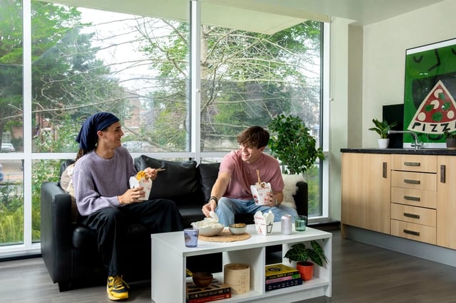 Two students eating take out on couch kitchen area at Beech House in Oxford Student Accommodation