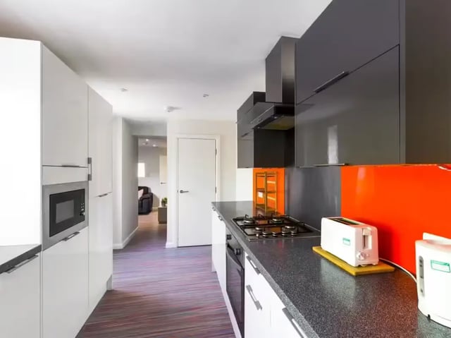 Modern kitchen with white cabinets microwave oven and cooker kitchen at 2 Queen Anne Street in Stoke-On-Trent Student Accommodation