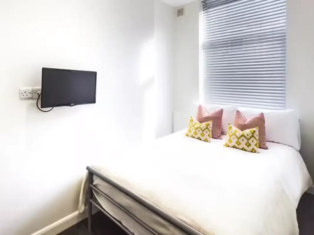 Bed with patterned pillows and TV bedroom at 2 Queen Anne Street in Stoke-On-Trent Student Accommodation