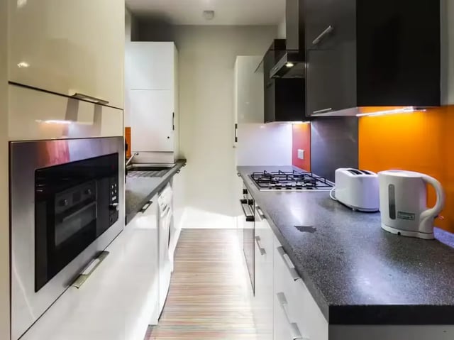 Modern kitchen with white appliances and orange backsplash Kitchen at 48 Cauldon Road in Stoke-On-Trent Student Accommodation