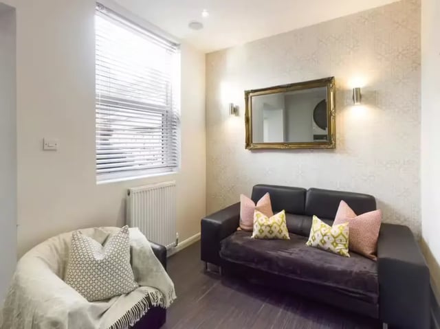 Dark sofa patterned pillows mirror and chair living room at 125 Leek Road in Stoke-On-Trent Student Accommodation