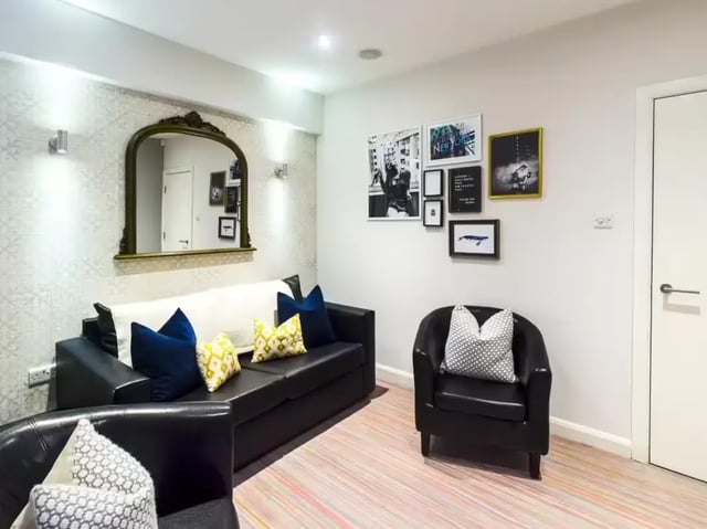 Black leather sofa mirror artwork striped floor living room at 6 Guildford Street in Stoke-On-Trent Student Accommodation