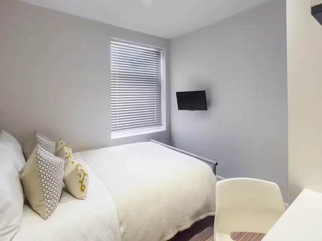 Bed with pillows television and chair bedroom at 6 Guildford Street in Stoke-On-Trent Student Accommodation