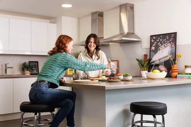 Two women eating at counter kitchen area at Brass Founders in Sheffield Student Accommodation