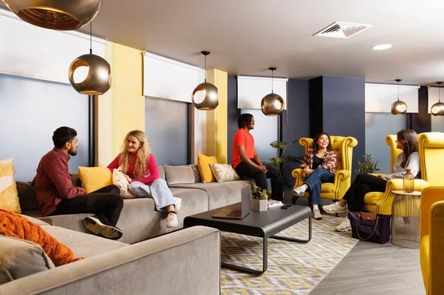 Students socializing on couches and chairs living room at Brass Founders in Sheffield Student Accommodation