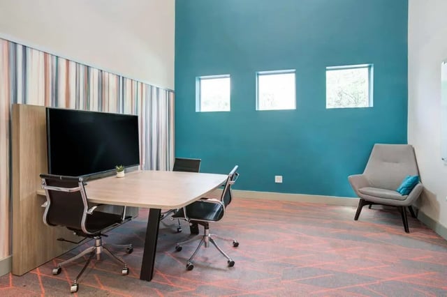 Table chairs TV and accent chair common area at Orion on Orpington in Orlando Student Accommodation
