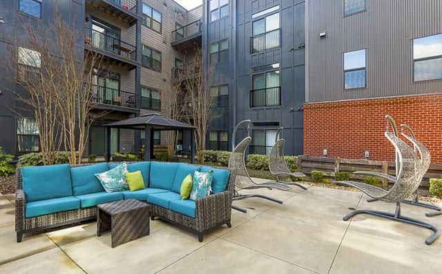 Sectional sofa and hanging chairs outdoor living area at Greene Crossing Apartments in Columbia Student Accommodation