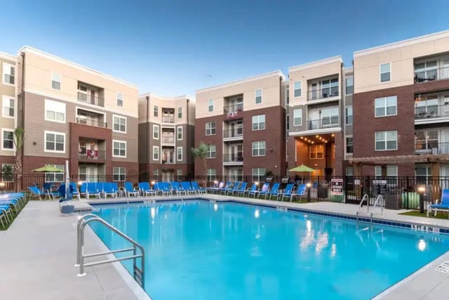 Apartment buildings surrounding large pool with lounge chairs exterior at Quantum On West Call in Tallahassee Student Accommodation