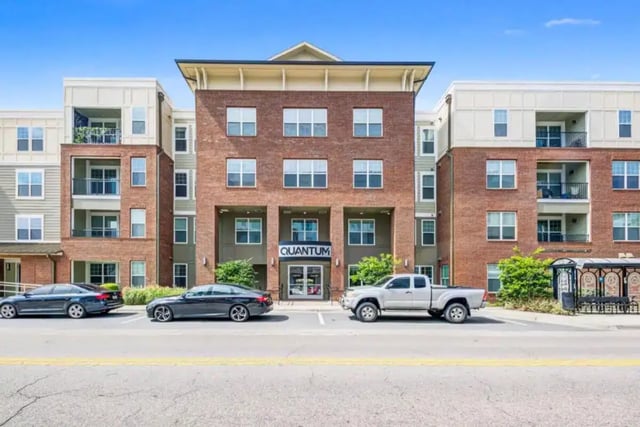 Modern apartment building with cars and bus stop exterior at Quantum On West Call in Tallahassee Student Accommodation