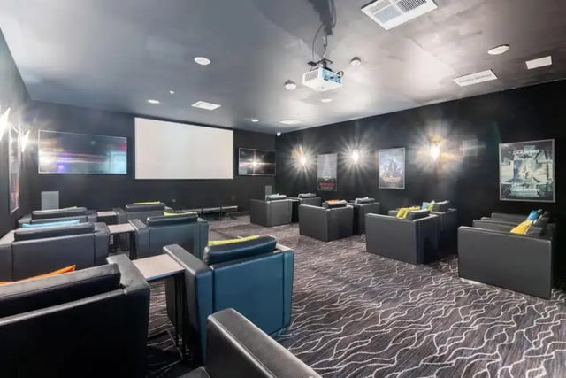 Theater room with black couches and projector screen Theater room at Quantum On West Call in Tallahassee Student Accommodation