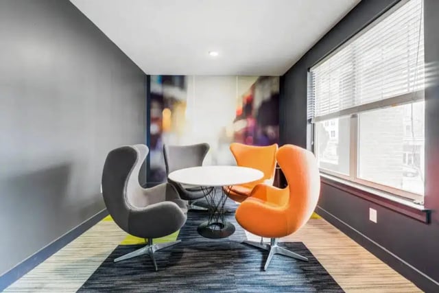 Modern chairs and table with city mural living room at Quantum On West Call in Tallahassee Student Accommodation