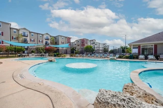 Pool with lounging chairs buildings exterior at Arba in San Marcos Student Accommodation