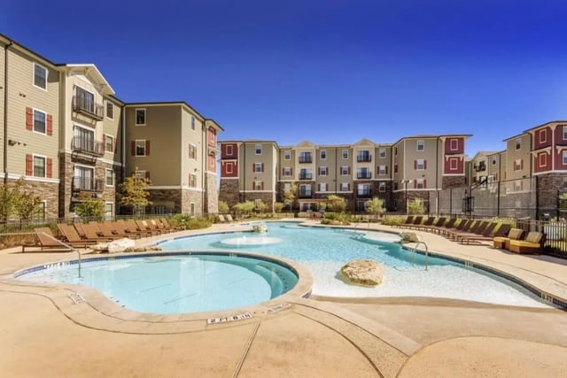 Apartment buildings and pool with lounge chairs exterior at Arba in San Marcos Student Accommodation