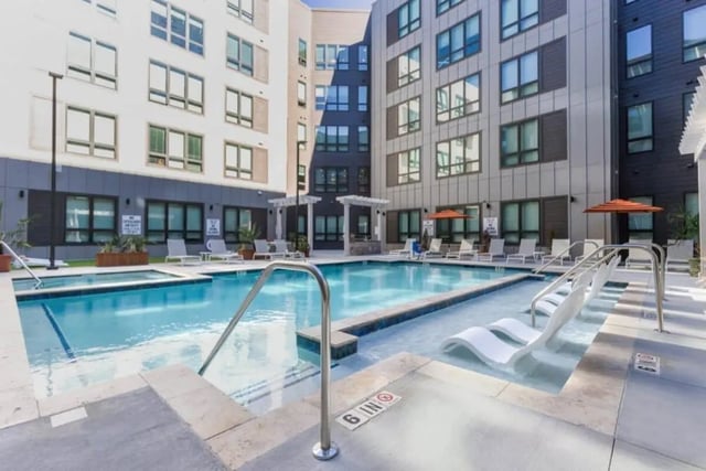 Modern apartment buildings surround a pool and hot tub at The Nest At University Center in Rock Hill Student Accommodation