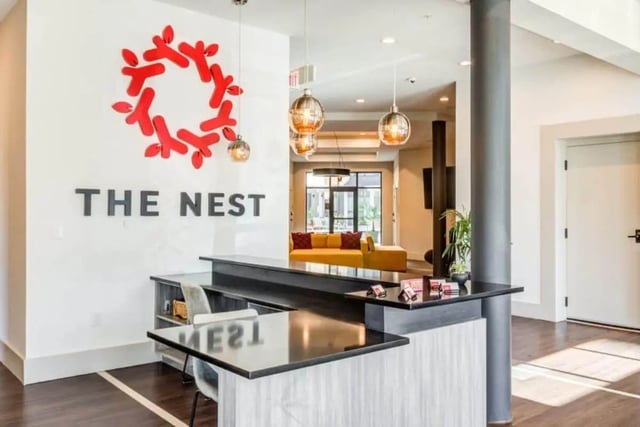 Reception desk with yellow sofa in background lobby at The Nest At University Center in Rock Hill Student Accommodation