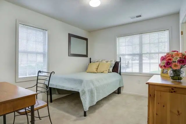 Bed with yellow pillows desk chair mirror bedroom at University Woods in Raleigh Student Accommodation