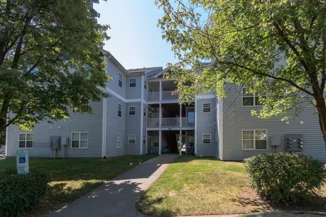 Apartment building with balconies and trees exterior at University Woods in Raleigh Student Accommodation