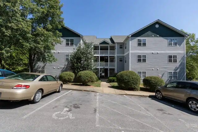 Apartment building with cars and trees exterior at University Woods in Raleigh Student Accommodation