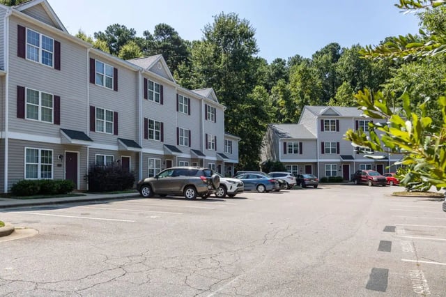 Townhouses with cars in parking lot exterior at Red Wolf Crossing in Raleigh Student Accommodation