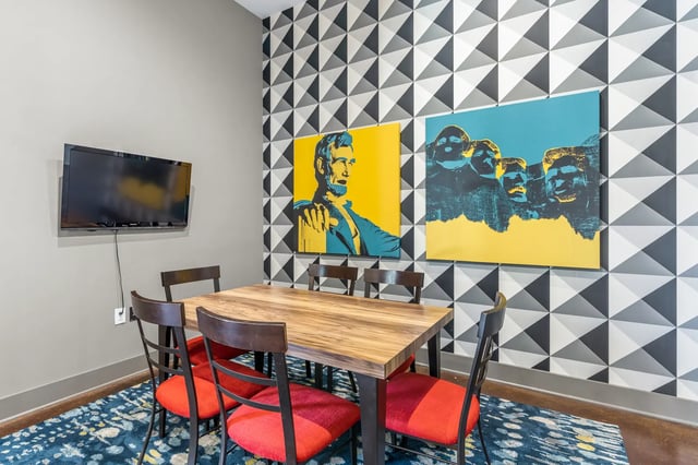 Dining table chairs wall art and TV common area at University Village at 2505 in Raleigh Student Accommodation