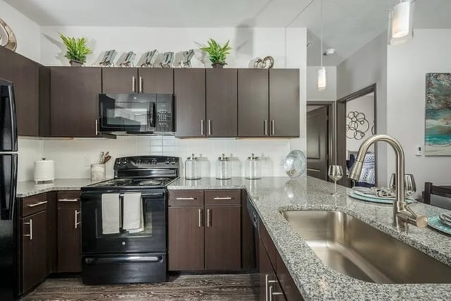 Dark cabinets microwave oven stovetop granite countertops kitchen at Cherry Street in College Station Student Accommodation