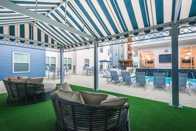 Woven couches by pool with lounge chairs exterior at Cherry Street in College Station Student Accommodation