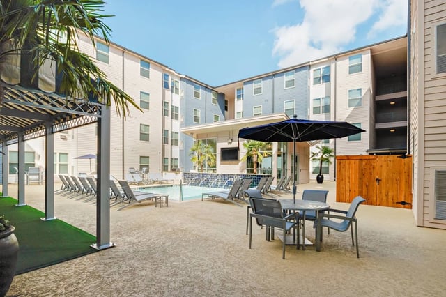 Pool lounge chairs umbrella outdoor seating exterior at Cherry Street in College Station Student Accommodation