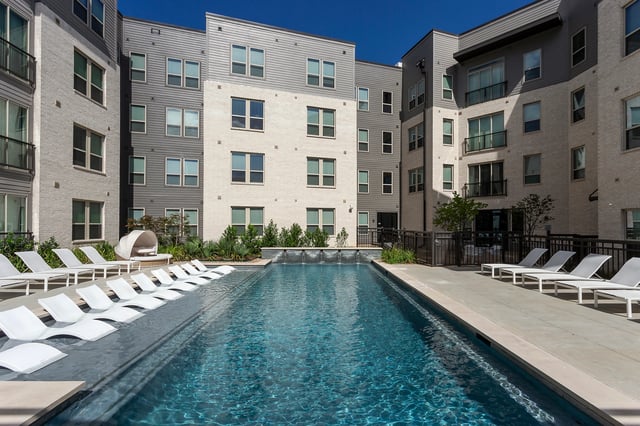 Pool with lounge chairs and modern apartment exterior at Berkeley House in College Station Student Accommodation