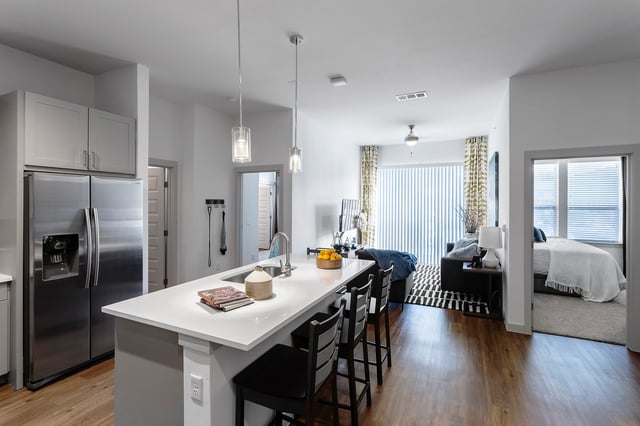 Modern kitchen island with bar stools and open bedroom at Berkeley House in College Station Student Accommodation