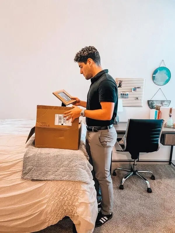 Man unpacking box on bed study area at The Hudson Northgate in College Station Student Accommodation