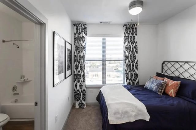 Bed with navy linens framed artwork and bathroom bedroom at The Hudson Northgate in College Station Student Accommodation