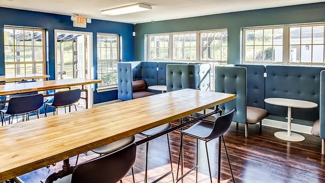 Wooden tables blue booths and chairs common area at The Hangout in Starkville Student Accommodation