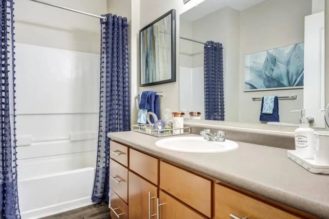 White bathtub blue shower curtain sink and vanity Bathroom at Madera in San Antonio Student Accommodation