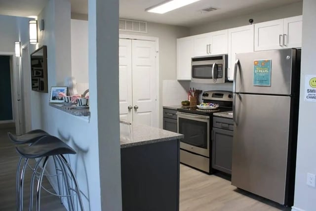 Modern kitchen with stainless steel appliances and stools kitchen at 21 Pearl in Austin Student Accommodation