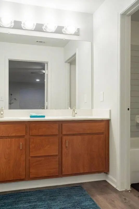 Double vanity with cherry cabinets and blue rug bathroom at Sparq On Rio in Austin Student Accommodation