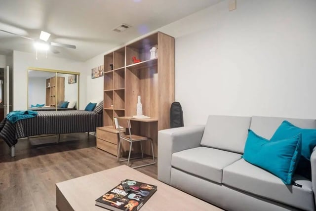 Bed couch bookshelf desk and mirror living room at Sparq On Rio in Austin Student Accommodation