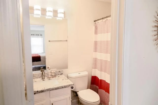 Vanity toilet and red striped shower curtain bathroom at Logan Square in Auburn Student Accommodation
