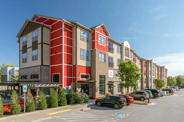 Apartment building with red accents parking lot exterior at Champions' Club in Fayetteville Student Accommodation