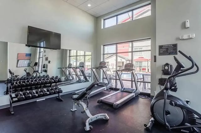 Dumbbells treadmills elliptical and bench gym area at Champions' Club in Fayetteville Student Accommodation