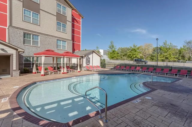 Pool with lounge chairs and cabanas exterior at Champions' Club in Fayetteville Student Accommodation