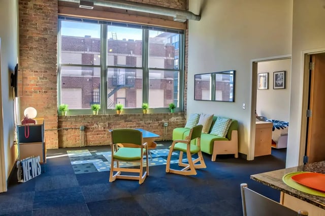 Green chairs table sofa overlooking building exterior living room at The Letterman Chicago in Chicago Student Accommodation
