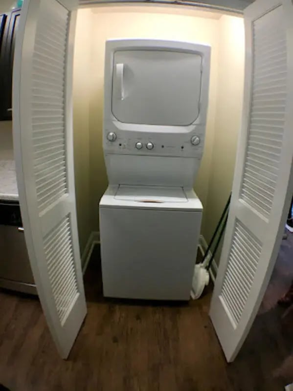 Stacked washer dryer with bi-fold doors Laundry Room at Seahawk Cove in Wilmington Student Accommodation