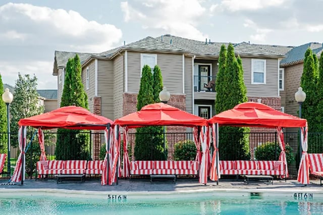 Red cabanas with striped seating by pool exterior at The Madison in Ames Student Accommodation