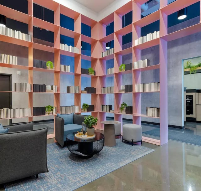 Pink bookshelves blue chairs coffee table lounge at The Connector in Atlanta Student Accommodation