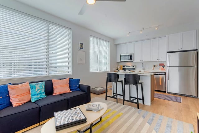 Sofa island kitchen white cabinets stainless steel refrigerator living room at The Connector in Atlanta Student Accommodation
